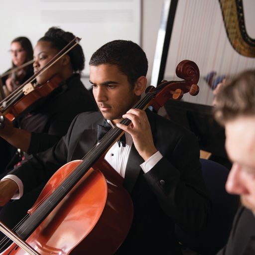 Students playing in the orchestra.  Featuring a cello player in the foreground