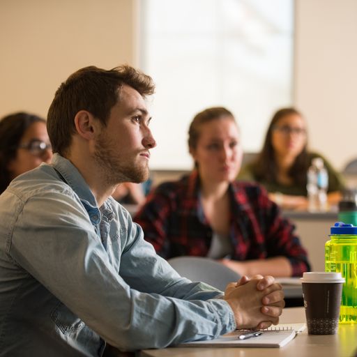 few college students in a classroom listening attentively